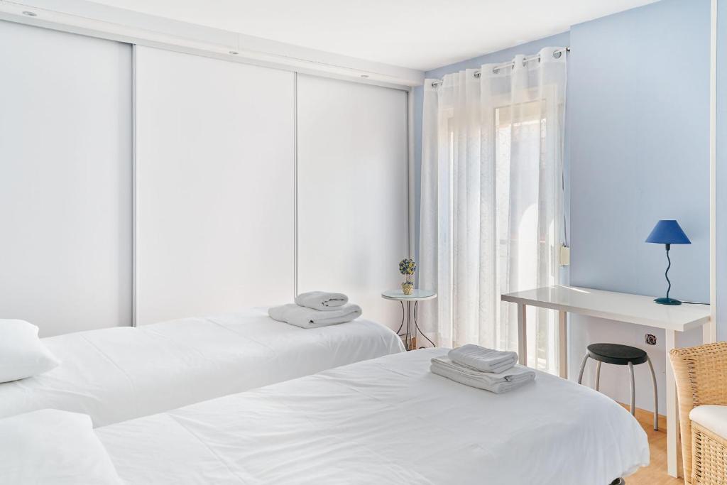 a white room with two beds and a table and a desk at Siena Urban Live Canarias in Santa Cruz de Tenerife
