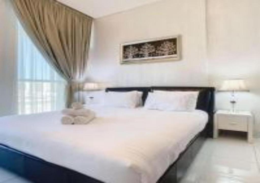 a bedroom with a large white bed with a teddy bear on it at Key View - Glamz Residence Tower 2 in Dubai