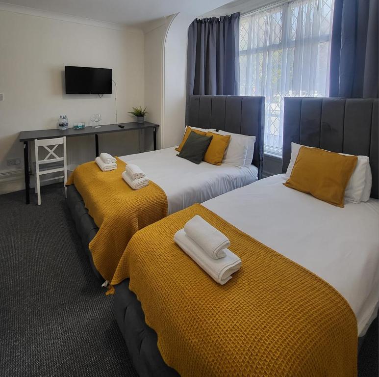 dos camas sentadas una al lado de la otra en una habitación en Woodford Hotel, en Londres