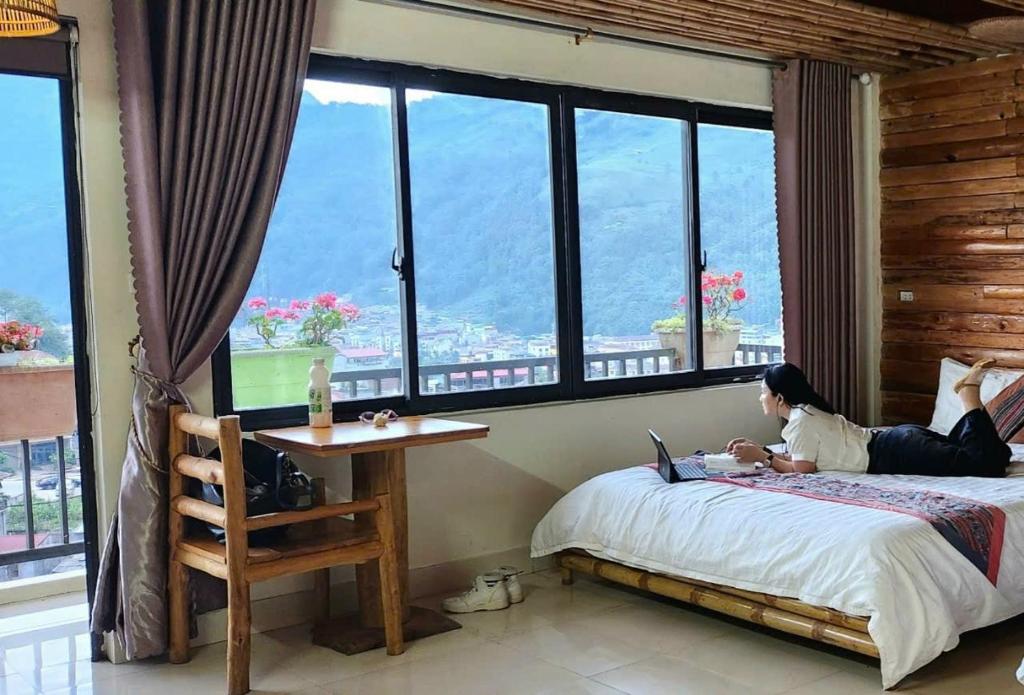 a woman laying on a bed with a laptop at Sapa indigo inn in Sapa