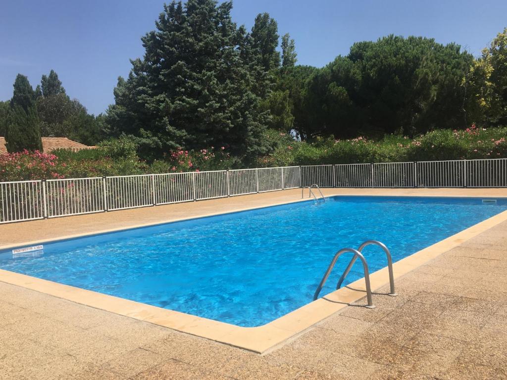 une piscine d'eau bleue et une clôture dans l'établissement Maison de vacances St Cyprien Plage, à Saint-Cyprien