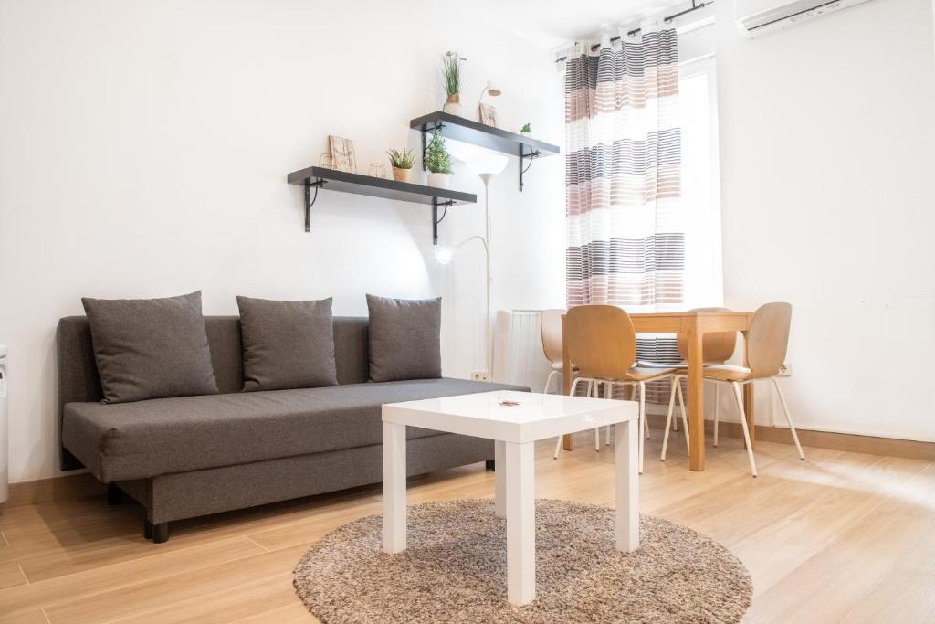 Renovado apartamento a 10 min del Aeropuerto y a 3 min de IFEMA في مدريد: غرفة معيشة مع أريكة وطاولة