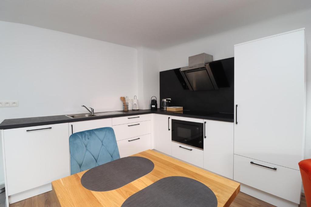 a kitchen with white cabinets and a tv and a table at Louisappart - Eupen Zentrum in Eupen