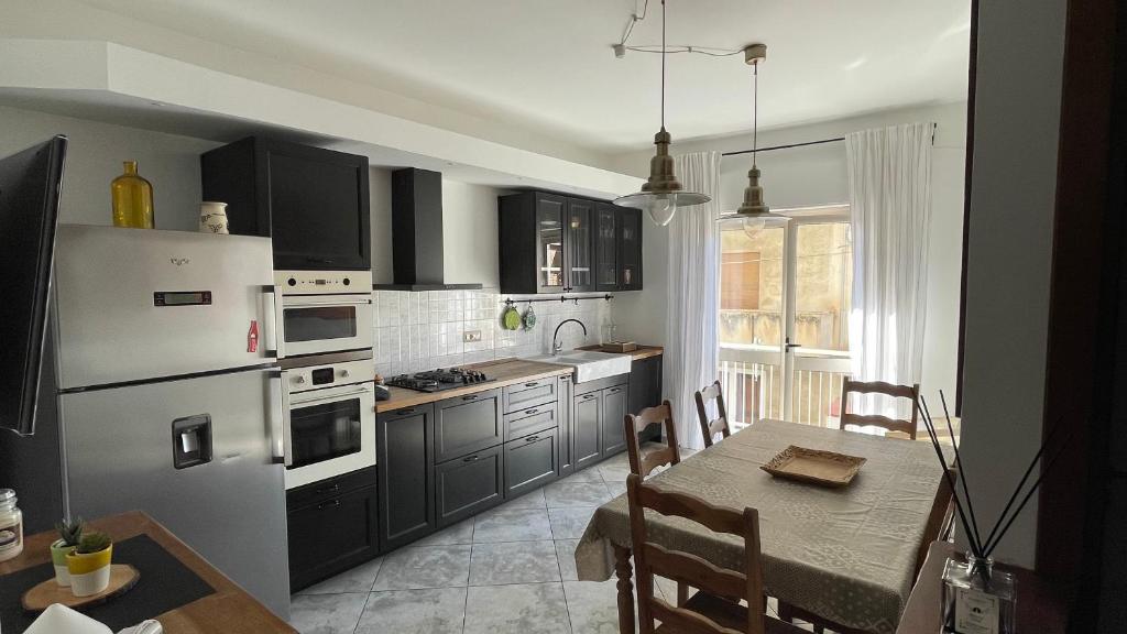 a kitchen with black cabinets and a table with a dining room at LT Apartment Tropea in Tropea