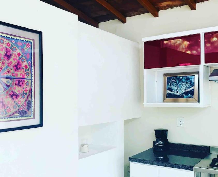 a kitchen with white cabinets and a painting on the wall at Casita Primavera / Casa Comalli in Comala
