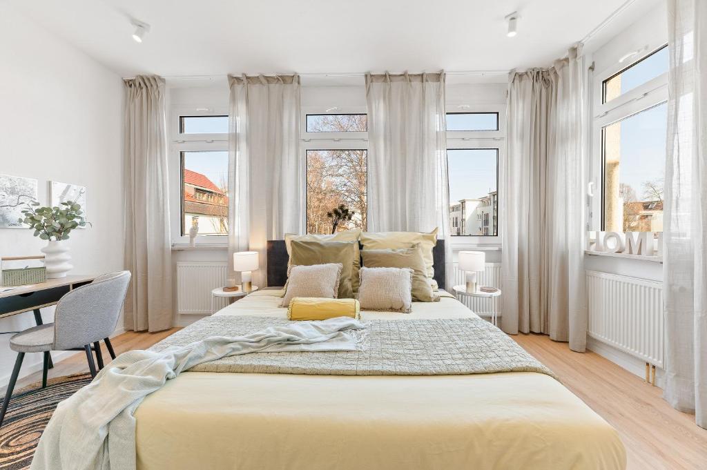een witte slaapkamer met een groot bed en ramen bij Helle zentrumsnahe familienfreundliche Ferienwohnung in Fellbach