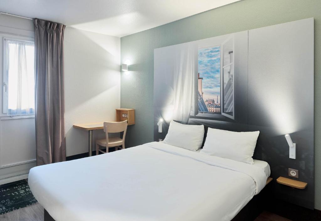 a hotel room with a large bed and a table at B&B HOTEL Bretigny-sur-Orge in Brétigny-sur-Orge