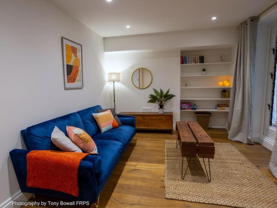 ein Wohnzimmer mit einem blauen Sofa und einem Tisch in der Unterkunft Central seaside home with peaceful patio in Brighton & Hove