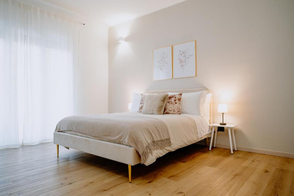 Un dormitorio con una cama grande con paredes blancas y suelos de madera. en Alatea Apartments Valverde, en Verona