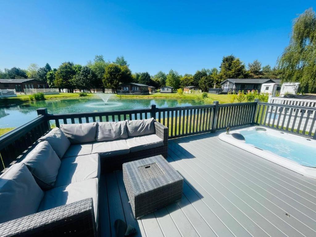 a patio with a couch and a swimming pool at The Waterhole Lodge with Hot Tub in Barmby on the Moor