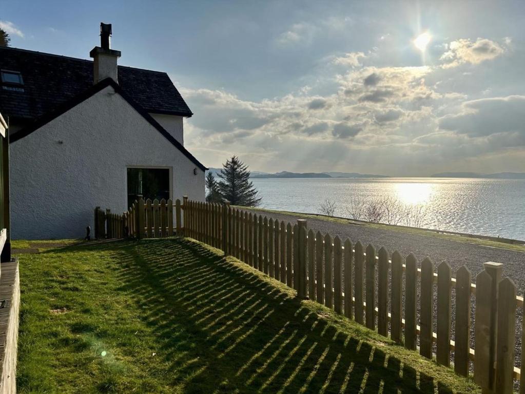 a white house with a fence next to the water at Craigneuk in Benderloch near Oban, stunning home with sea views in Oban