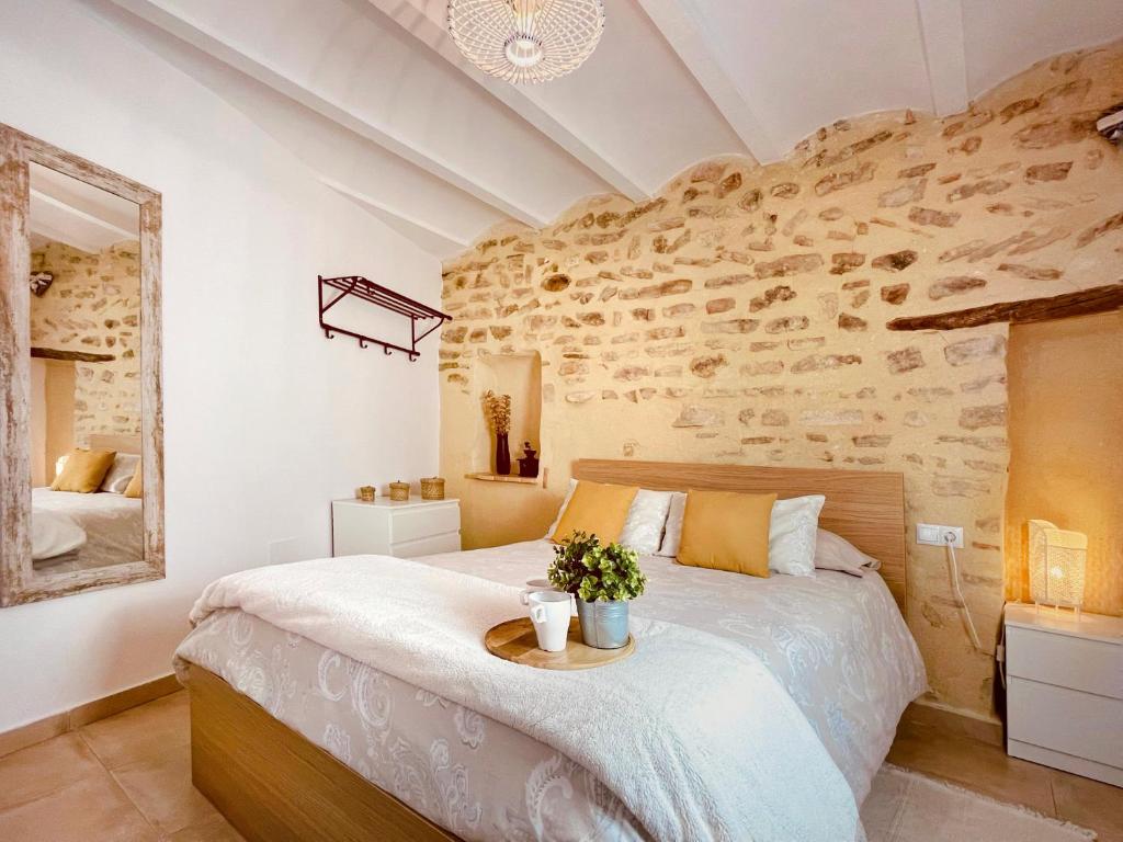 1 dormitorio con 1 cama grande y pared de piedra en Ca Dioniso en Planes