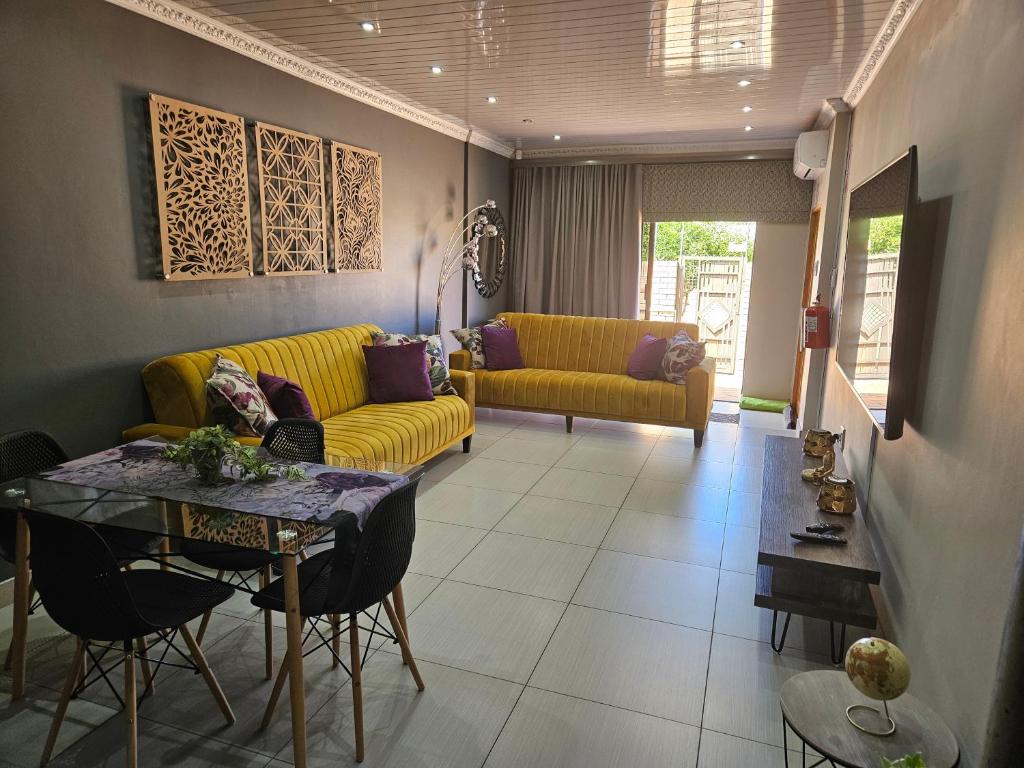 a living room with a yellow couch and a table at Molozi in Kimberley