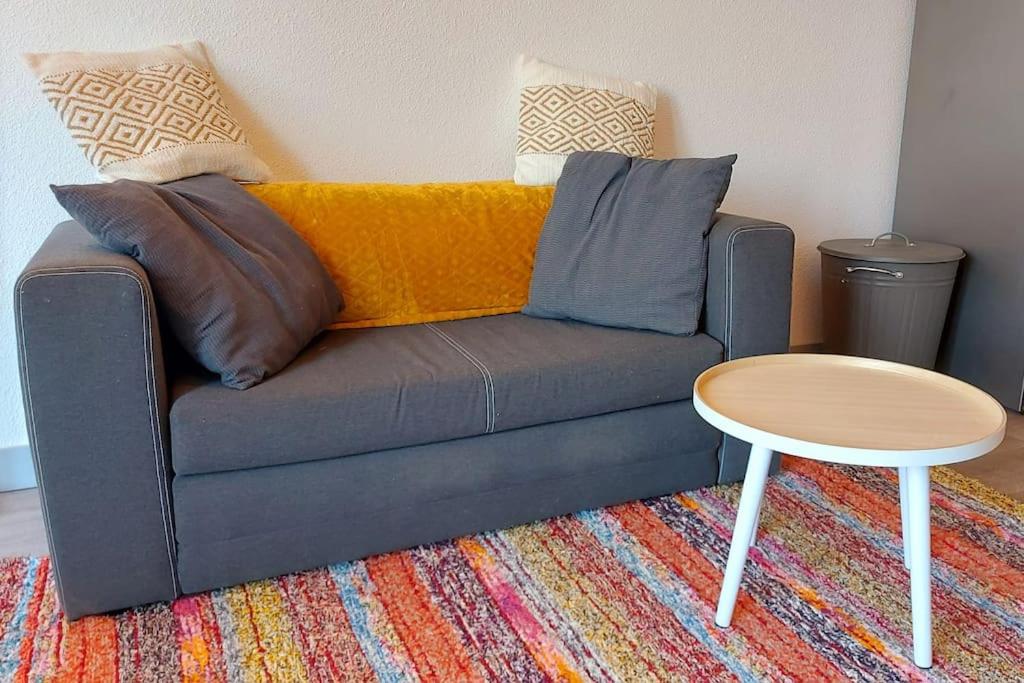 ein Sofa mit Kissen und einen Tisch in einem Zimmer in der Unterkunft Cosy Zenith Purpan in Toulouse