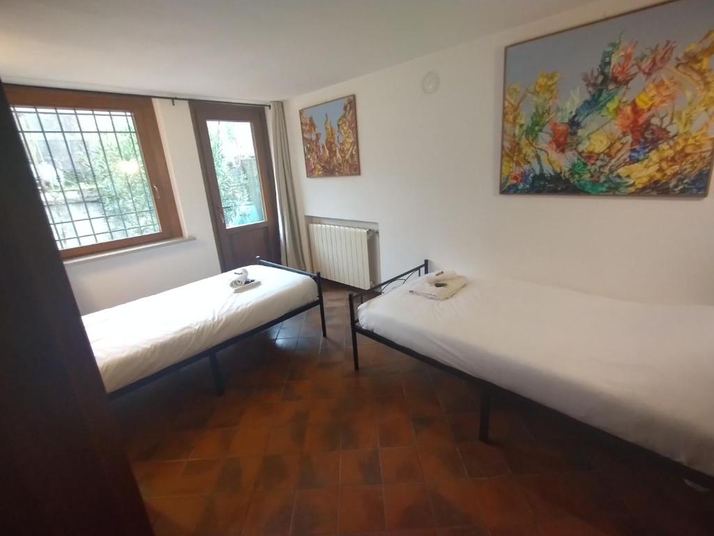 two beds in a room with two windows at La Casa Veneta - Hostel in Muggia