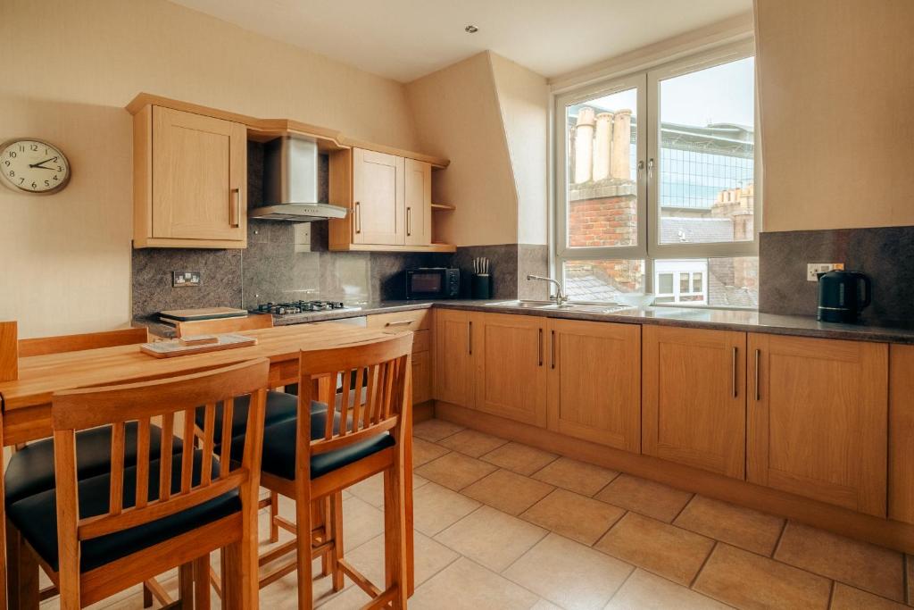 a kitchen with wooden cabinets and a table with chairs at Fonthill Residence - SJA Stays - 1 Bed Apartment in Aberdeen