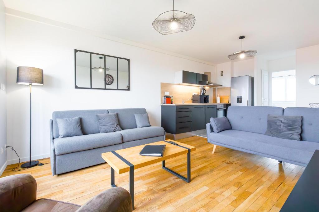 uma sala de estar com dois sofás azuis e uma mesa em LE PANORAMA à deux pas du centre ville em Dijon