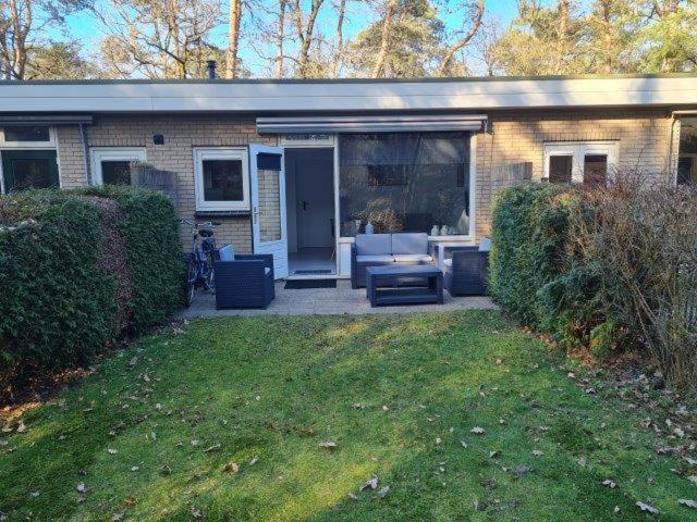 een stenen huis met een patio en een tuin bij Natuurhuisje in Otterlo