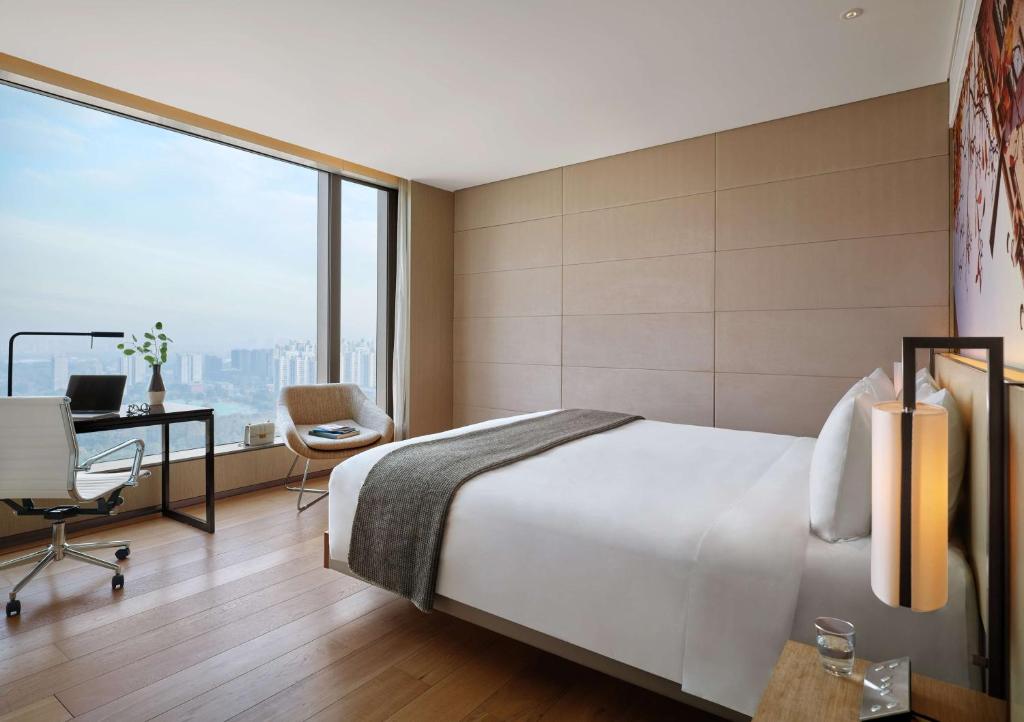 een hotelkamer met een bed, een bureau en een raam bij East Beijing in Beijing