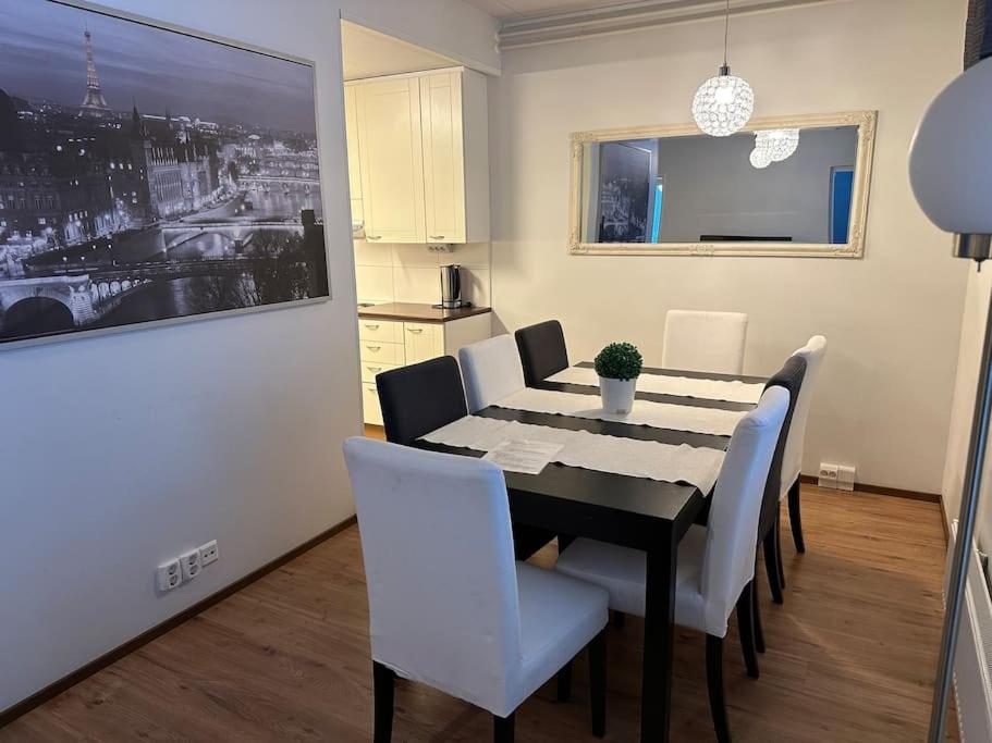 a dining room with a black table and white chairs at ”Paris” -2BR with sauna&balcony in Tornio