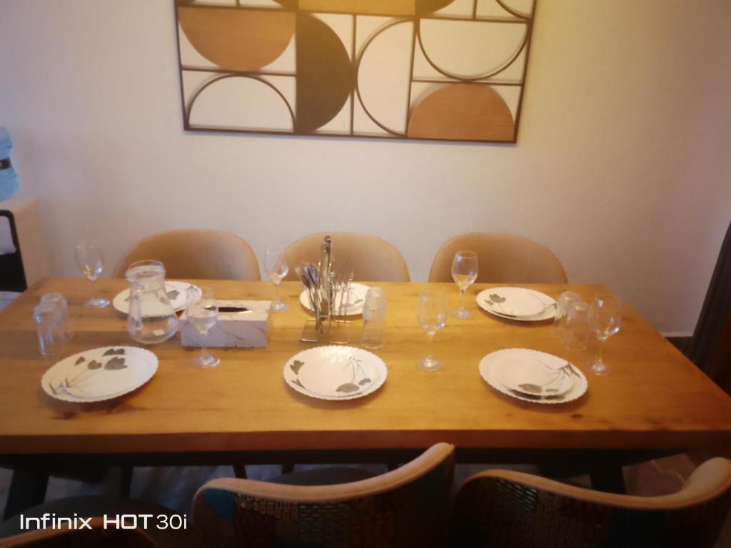 a wooden table with plates and wine glasses on it at Macgregor Apartment in Nairobi