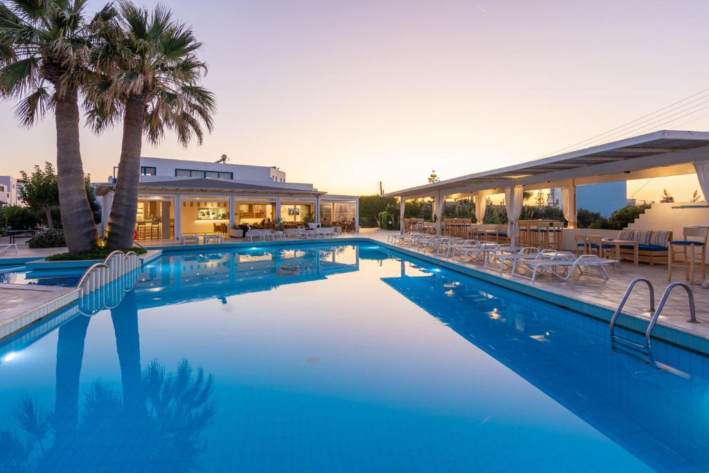 a large swimming pool with chairs and a building at Hotel Hara Ilios Village in Gouves