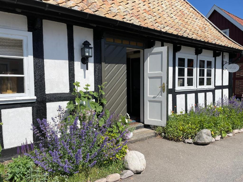 ein schwarzes und weißes Haus mit Blumen davor in der Unterkunft Elins Lycka i Viken in Viken