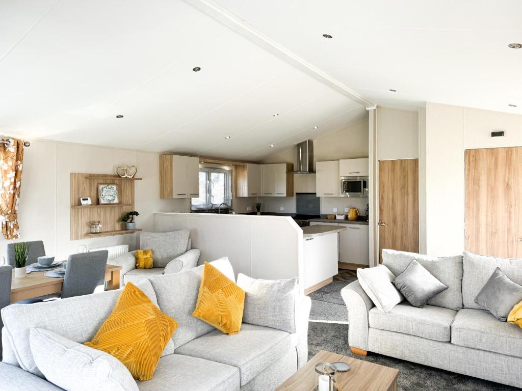 a living room with two couches and a kitchen at Holidays with TLC at Barlings Country Park in Lincoln