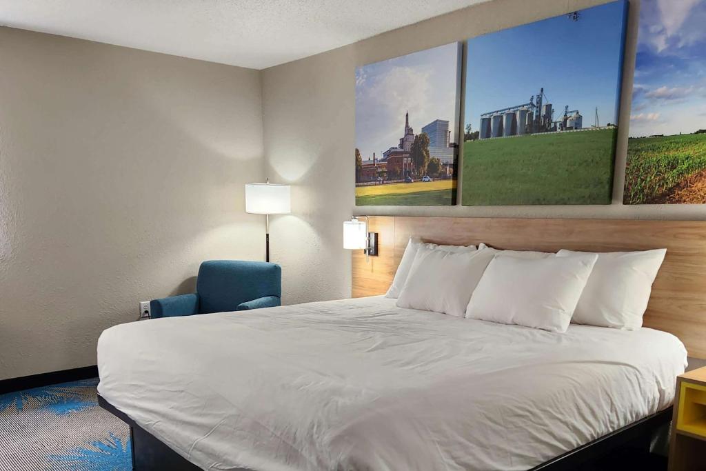 a hotel room with a bed and a blue chair at Days Inn by Wyndham Davenport in Davenport