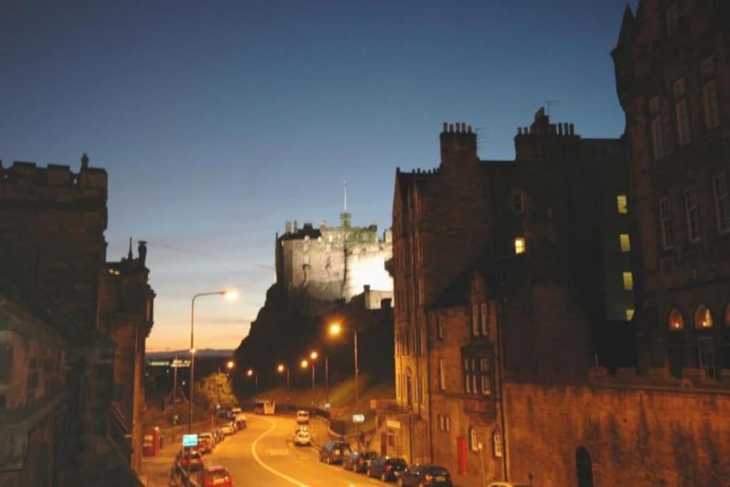 a city street at night with a castle in the background at Lovely 2 bed flat located next to Edinburgh Castle in Edinburgh