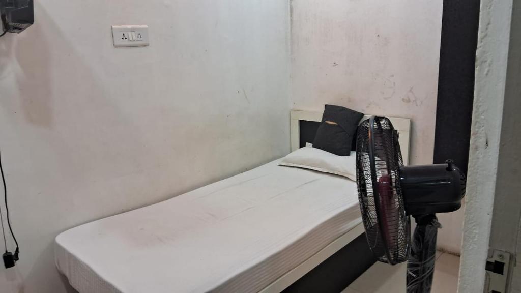 a small bed in a room with a fan at CHENNAI PLAZA in Chennai
