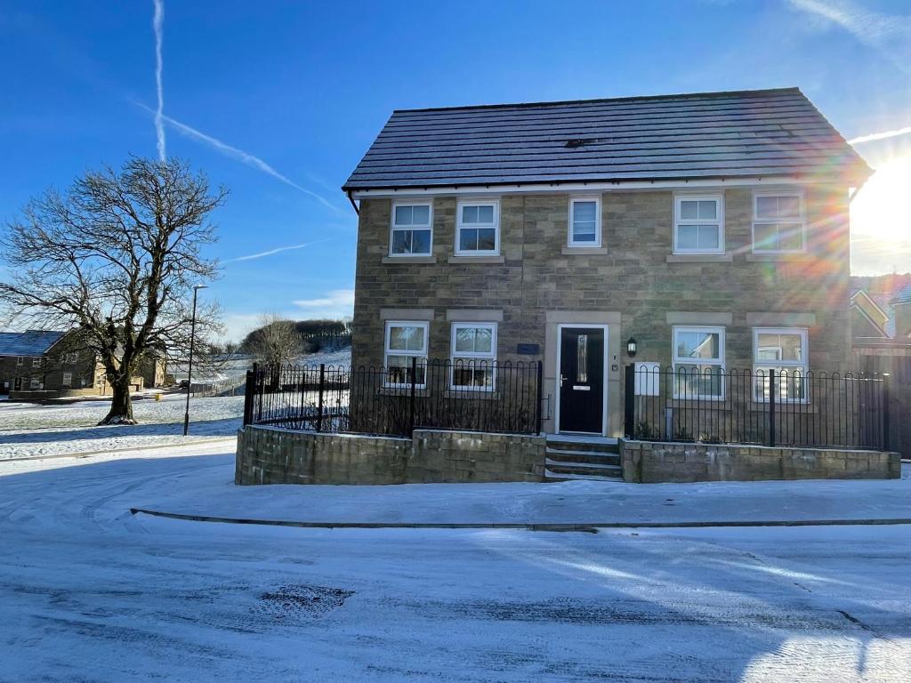 a brick house on a street with snow on the ground at Peak View - Modern Cottage in Buxton
