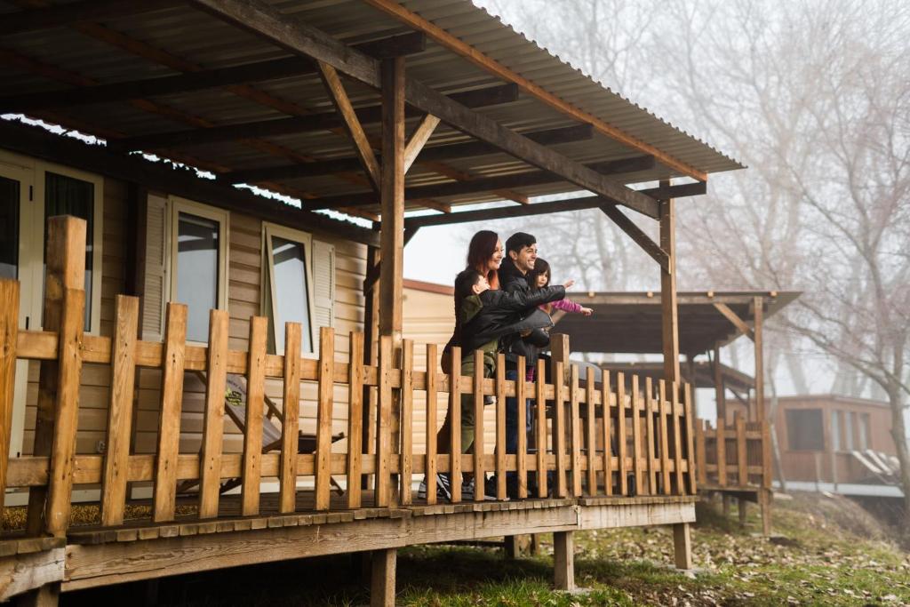 zwei Frauen sitzen auf einem Zaun vor einem Haus in der Unterkunft Tóparti Safari-ház a Richter Safari Parkban in Nagykőrös
