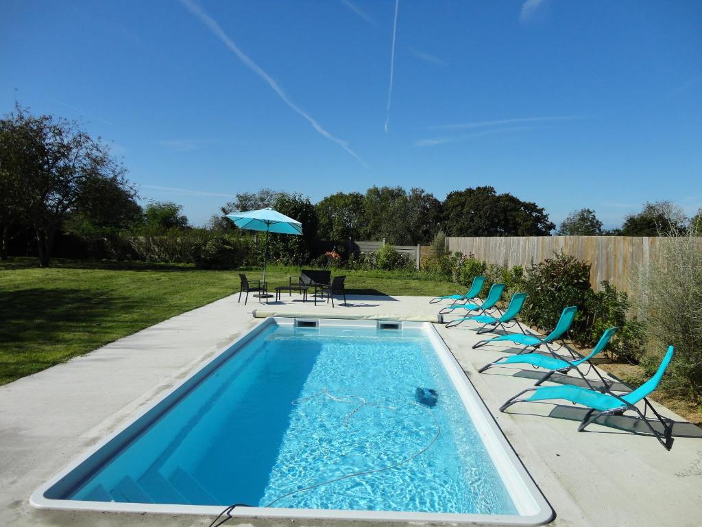 a swimming pool with chairs and an umbrella at Les Grandes Landes - Piscine privée - Grand jardin in Cricqueville-en-Bessin