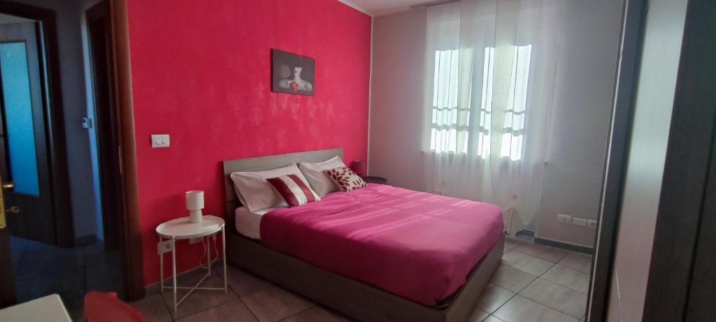 Casa Graziella- appartamenti vacanze في Portacomaro: غرفة نوم حمراء مع سرير وبطانية وردية