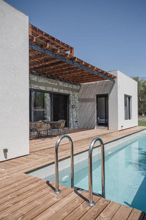 a house with a swimming pool and a wooden deck at NIMA Suites in Paleros