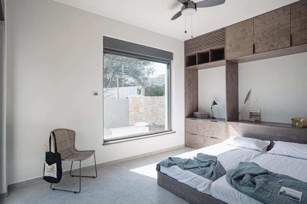 a bedroom with a bed and a chair and a window at NIMA Suites in Paleros