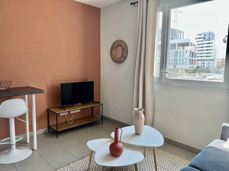 ein Wohnzimmer mit 2 Tischen und einem TV in der Unterkunft Studio Saint-Roch in Montpellier