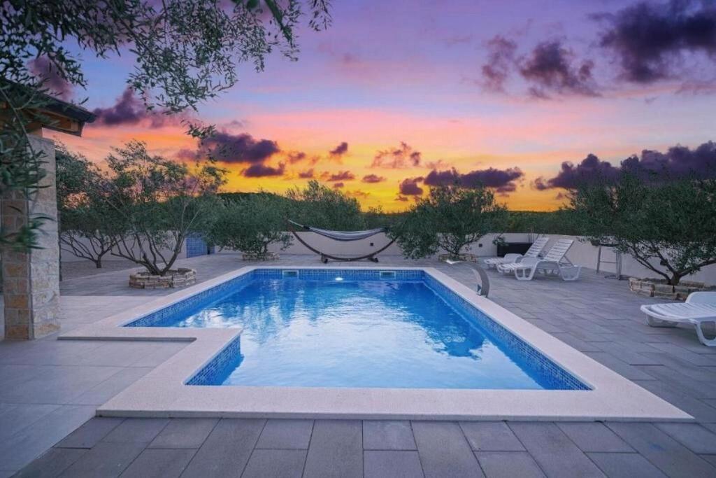 a swimming pool with a sunset in the background at Villa Ivana Whisper of nature in Vodice