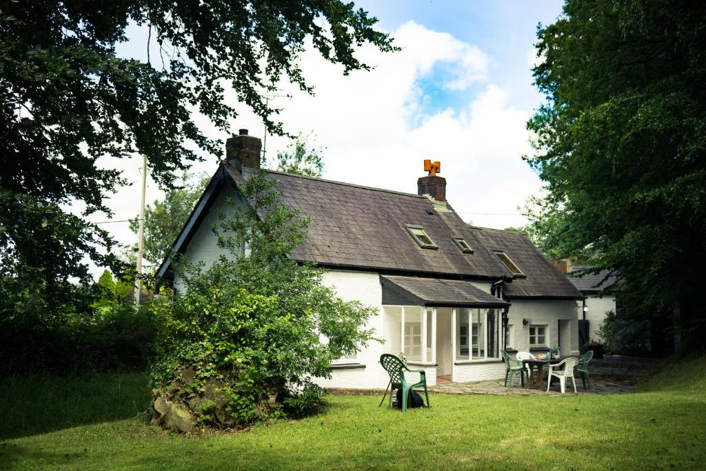 a white house with a table and chairs in the yard at Garden Cottage Newcastle Emlyn in Newcastle Emlyn