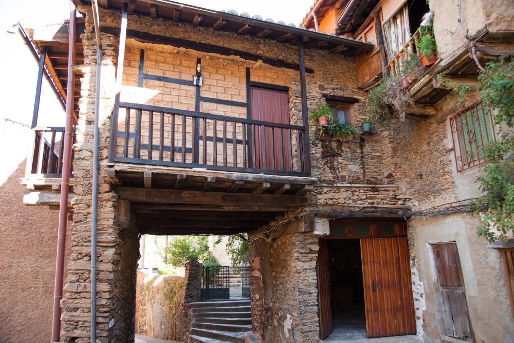 un antico edificio in pietra con balcone e scale di Casa Rural Valle del Arrago a Robledillo de Gata