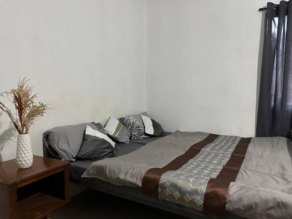 a bedroom with a bed with pillows and a table at House in Coron-The Grey House in Coron