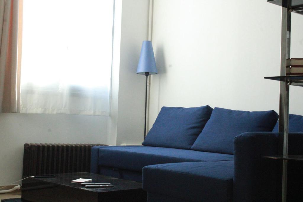 - un canapé bleu dans le salon avec une lampe dans l'établissement Versailles Direct : T2 Authentique et Chaleureux, à Versailles