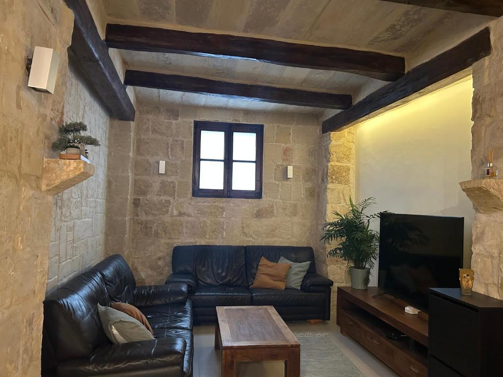 a living room with a leather couch and a table at Traditional House of Character with Terrace - Central, Cozy & Calm in Birkirkara