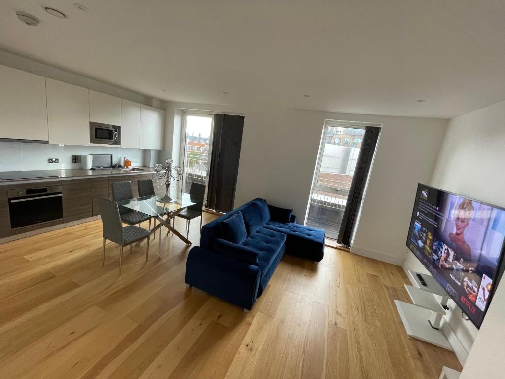 Luxury Top Floor Penthouse Apartment near Heathrow في لندن: غرفة معيشة مع أريكة زرقاء وطاولة