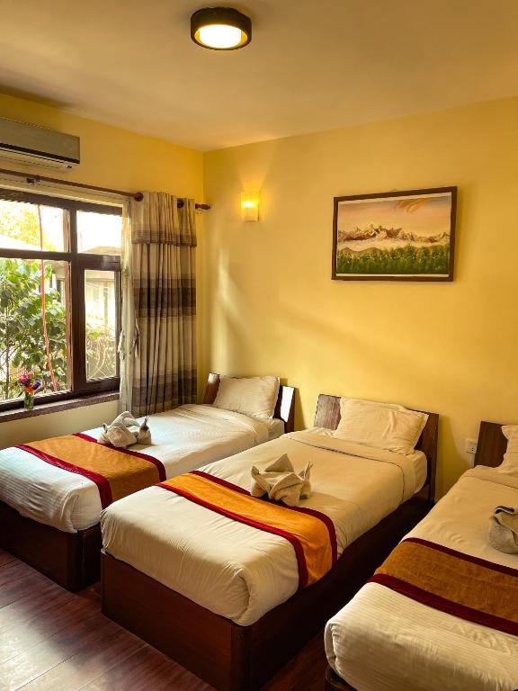 Una habitación de hotel con tres camas en una habitación. en Hotel Atlantic, en Katmandú