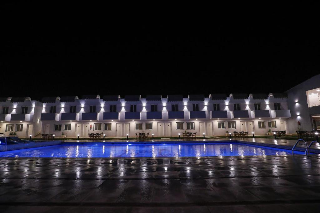 un edificio con una piscina delante de él por la noche en Hotel Royal Plaza, en Asiut