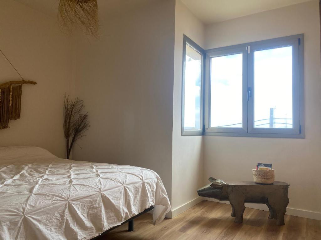 Schlafzimmer mit einem Bett, einem Tisch und einem Fenster in der Unterkunft Casa Tela Marinera in Cotillo