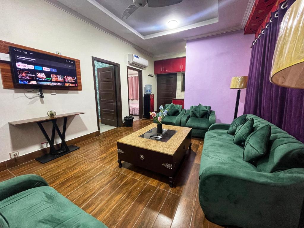 salon z zielonymi kanapami i telewizorem z płaskim ekranem w obiekcie Danny Luxe Apartments w mieście Islamabad