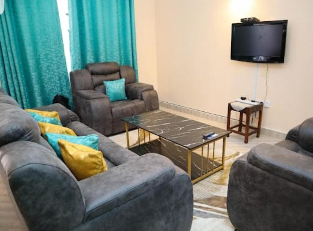 sala de estar con 2 sofás y TV en bluesky en Nairobi